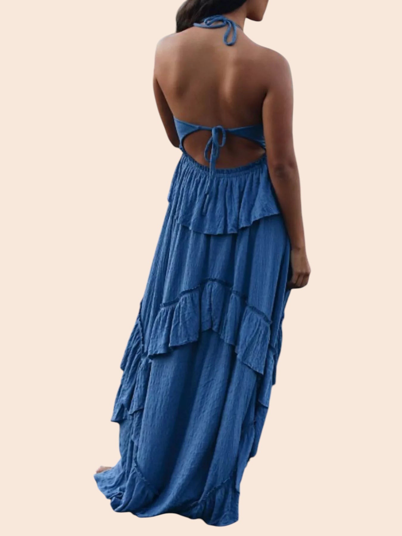 My Store blue ruffled tiered halter maxi dress with an open back, worn by a woman on a rocky beach.
