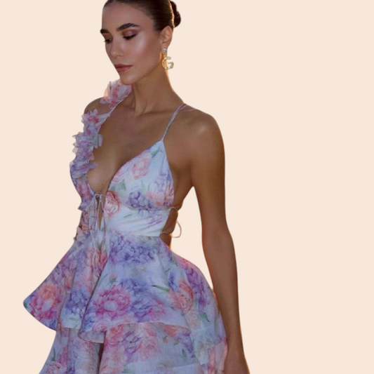 My Store floral ruffle halter mini dress with a plunging neckline and pastel print worn by a model on a beach.