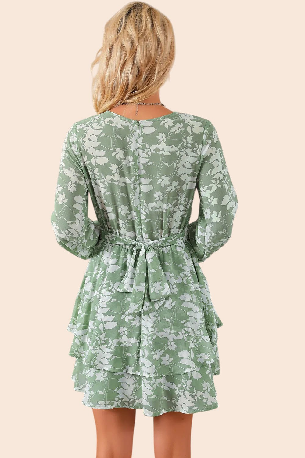 Back view of a My Store floral mini dress in sage green with long sleeves, a tied waist, and a tiered ruffle skirt.