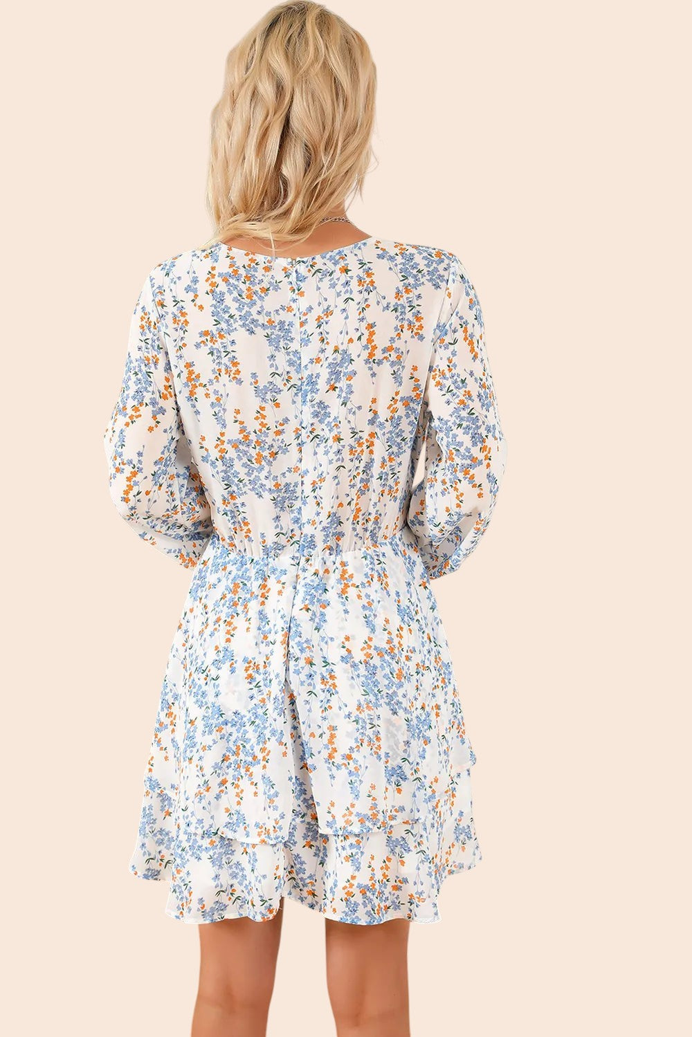 Back view of a blonde woman wearing a My Store floral mini dress with long balloon sleeves and a tiered skirt.