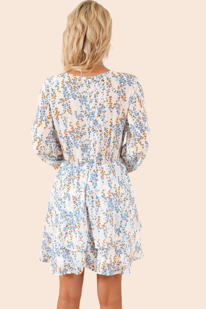 Back view of a blonde woman wearing a My Store floral mini dress with long balloon sleeves and a tiered skirt.