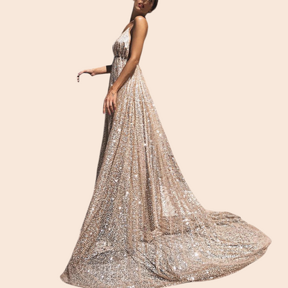 My Store Aurelia gold shimmer plunge maxi gown with a deep V-neckline and full floor-length skirt on a stone street.