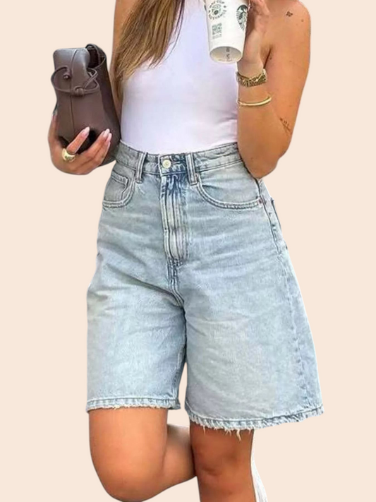 My Store high-waisted light-wash denim Bermuda shorts with a raw hem worn by a woman with a white tank top
