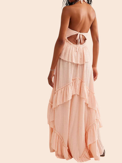 Back view of a My Store ruffled tiered halter maxi dress in soft peach with an open back and flowing skirt
