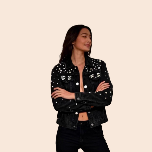 A woman wearing a My Store black denim jacket with silver stud embellishments, styled with black jeans in a gallery.