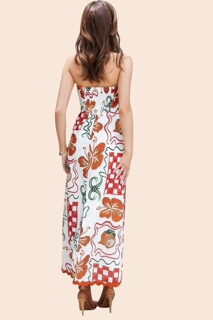 My Store strapless maxi dress with a colourful tile and floral print, worn by a woman standing by a resort pool.