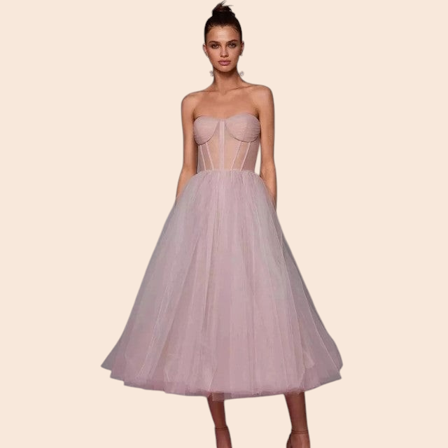 Model wearing a My Store Vivienne blush pink strapless corset midi dress with a voluminous layered tulle skirt