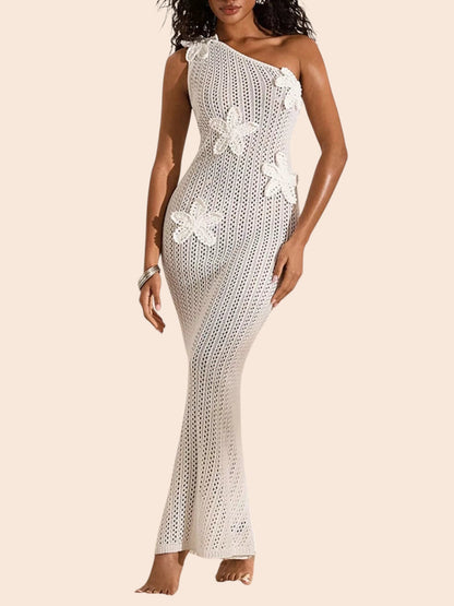 My Store white one-shoulder crochet maxi dress featuring dimensional floral appliqués on a sandy beach backdrop.